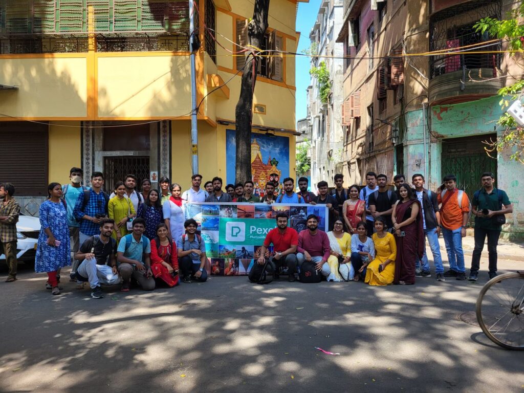A vibrant group of photographers posing during a photowalk in Kolkata's urban streets, showcasing diverse culture.