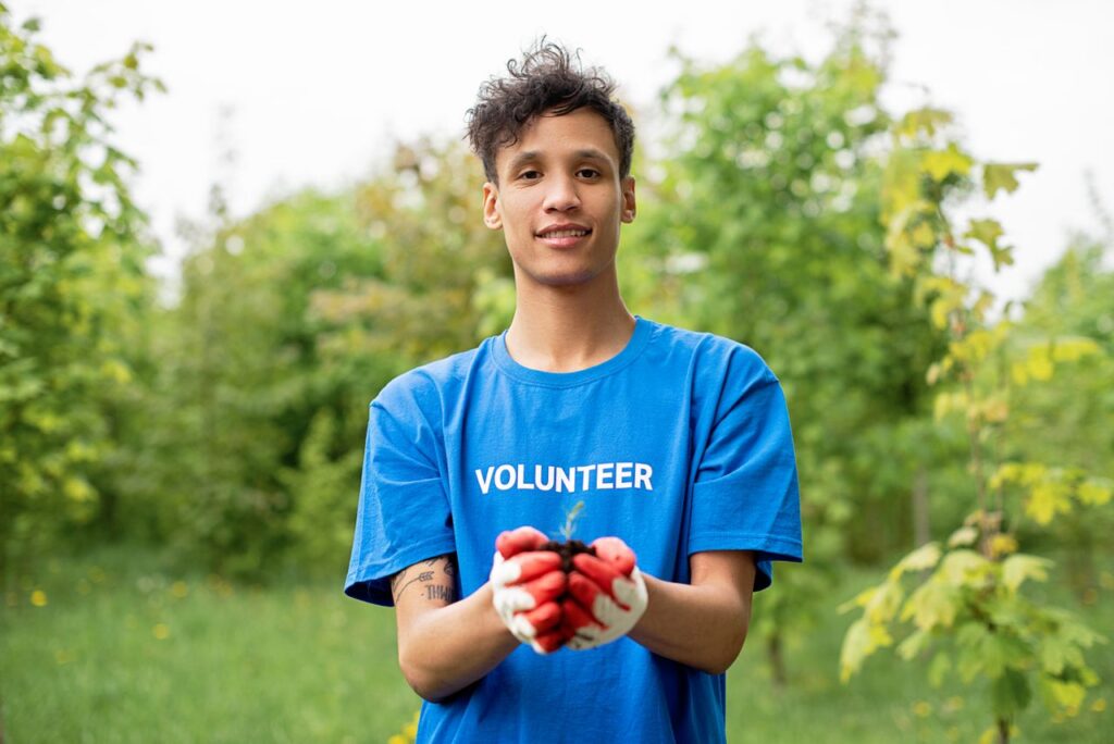 A young male volunteer holding a seedling, promoting environmental conservation.